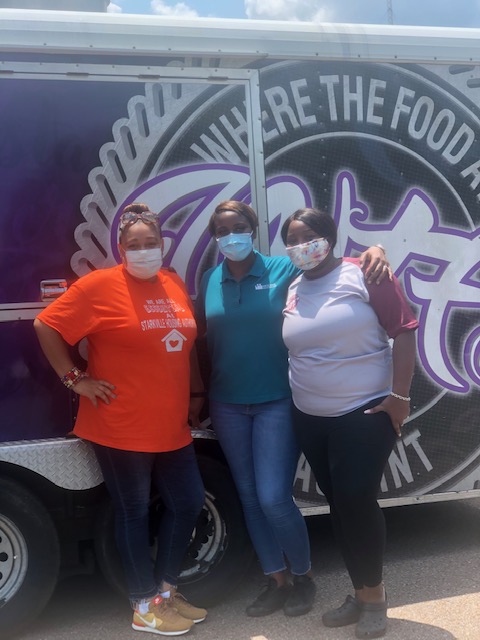 Three women posing in front of the food truck